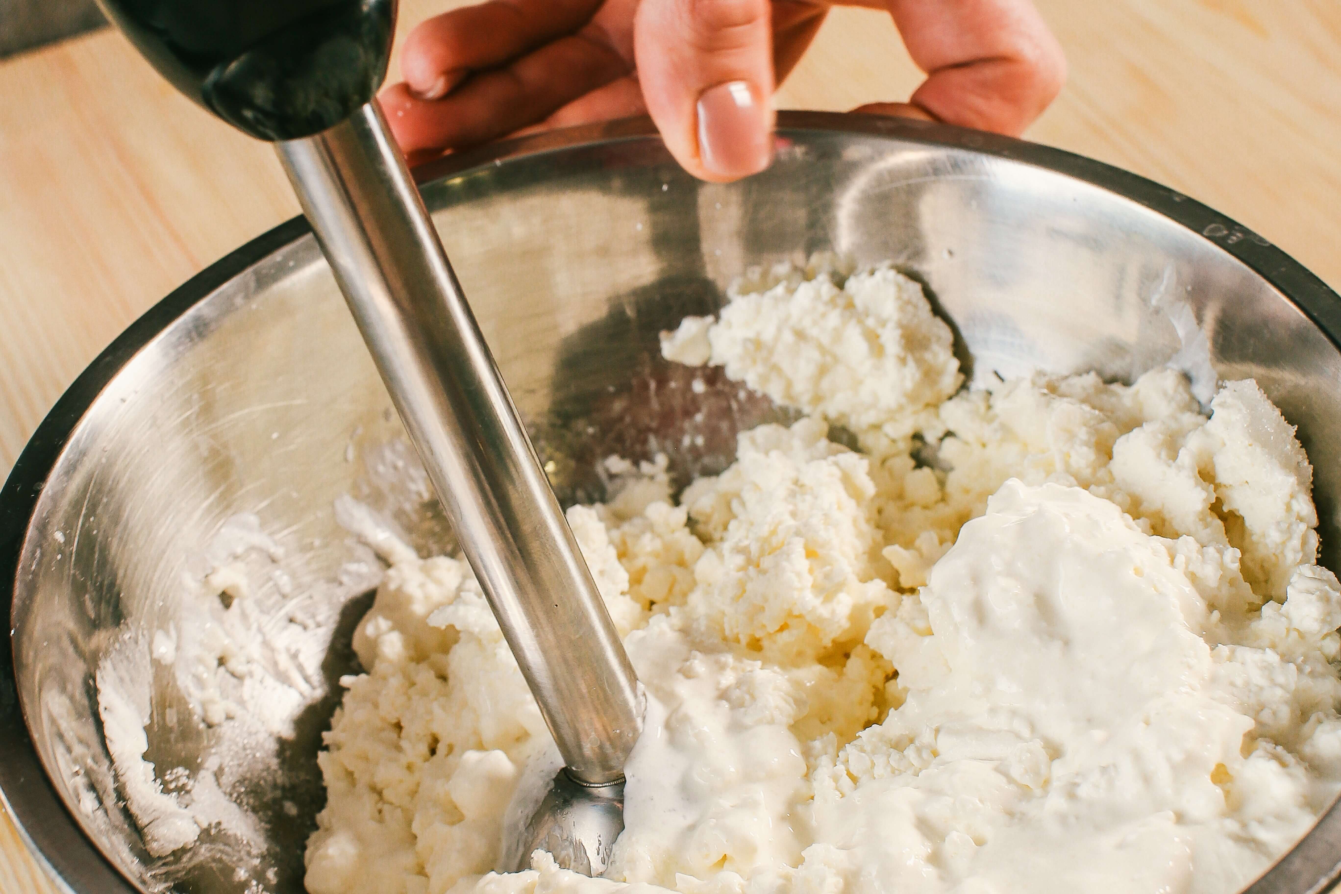  Сир та 50 мл вершків збити блендером максимально досягаючи однорідності. Цукор та воду треба закипятити  в сотейнику, і довести до температури 117°C. Коли сироп матиме температуру 90 °C, починайте міксером збивати яйця. Тоненькою цівкою вливаємо наш сироп в яйця - це називається «пат а бомб». Міксер вимикаємо, коли маса буде білою та стійкою. Холодні вершки (200 мл) збити з ваніллю до стійких піків. Всі три складові - сир, пат а бомб, вершки змішати дуже делікатно за допомогою вінчика та силіконової лопатки. Додати цедру.